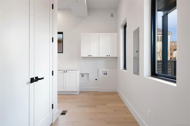 clothes washing area with electric dryer hookup, hookup for a washing machine, cabinets, and light hardwood / wood-style floors