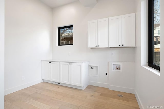 clothes washing area with hookup for an electric dryer, cabinets, light wood-type flooring, and hookup for a washing machine