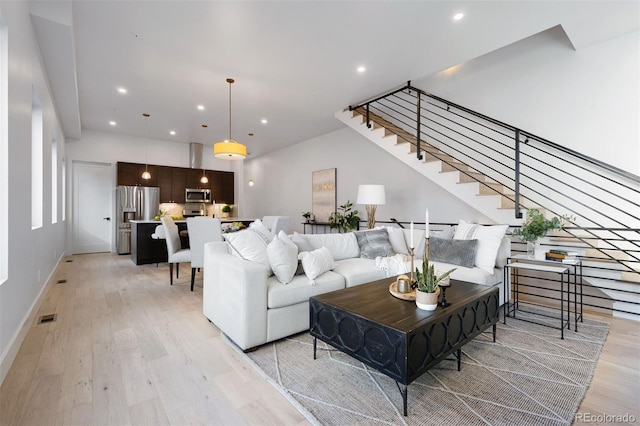 living room with stairway, light wood-style flooring, visible vents, and recessed lighting