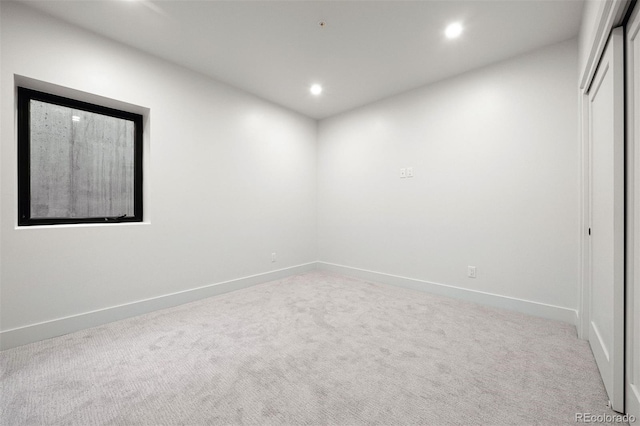 spare room with recessed lighting, baseboards, and light colored carpet