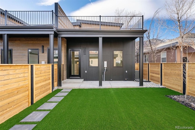 rear view of property with a patio area, a fenced backyard, a yard, and a balcony