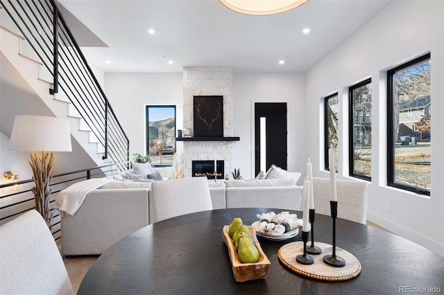 dining space with recessed lighting, a large fireplace, wood finished floors, baseboards, and stairway