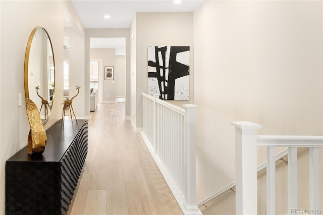 corridor featuring light wood-type flooring, baseboards, an upstairs landing, and recessed lighting
