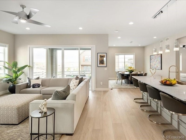 living room with light wood-style floors, baseboards, a ceiling fan, and recessed lighting