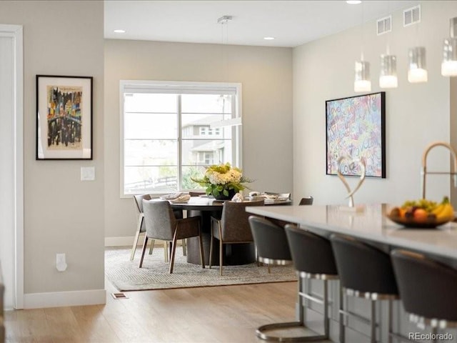 dining room featuring visible vents, baseboards, and light wood-type flooring