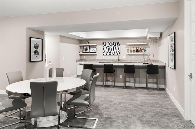 dining room with indoor wet bar, baseboards, and carpet floors