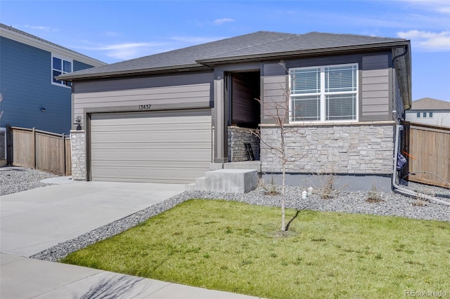 view of front of home with a front yard, fence, concrete driveway, an attached garage, and stone siding