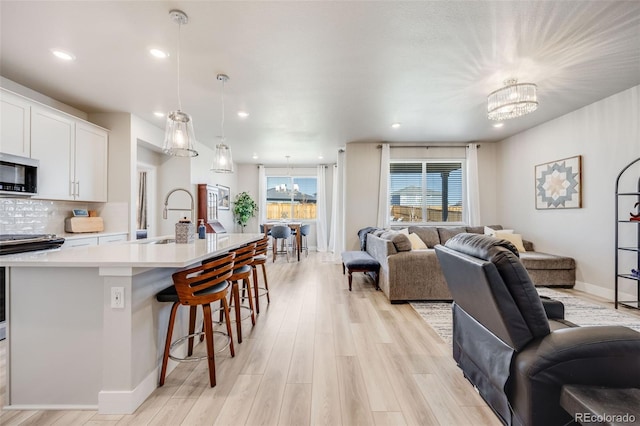 living area with recessed lighting, baseboards, a chandelier, and light wood-type flooring