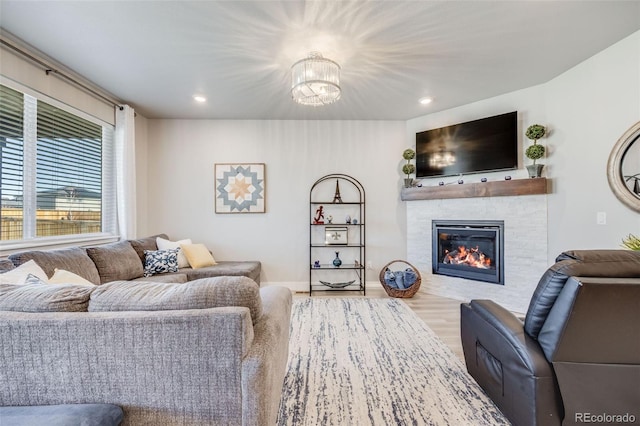 living room featuring recessed lighting, a notable chandelier, a tiled fireplace, and wood finished floors