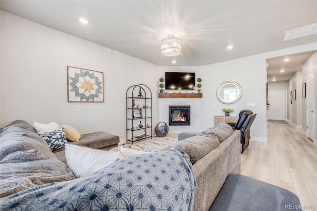 living area featuring recessed lighting, visible vents, a glass covered fireplace, and light wood-type flooring