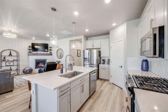 kitchen with tasteful backsplash, a sink, light countertops, open floor plan, and stainless steel appliances