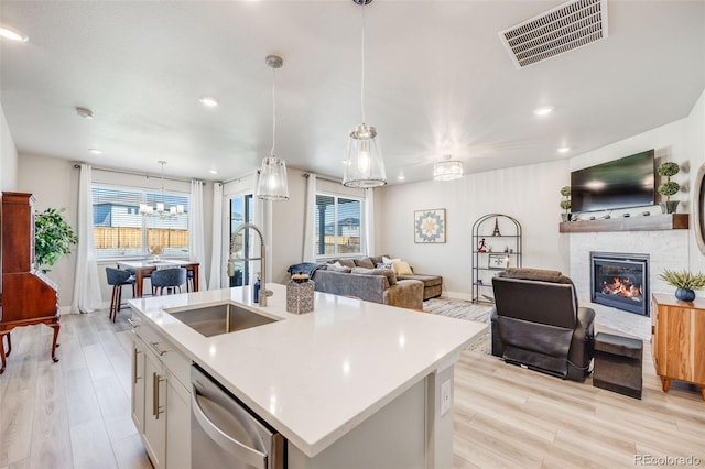 kitchen featuring a sink, dishwasher, light countertops, open floor plan, and visible vents