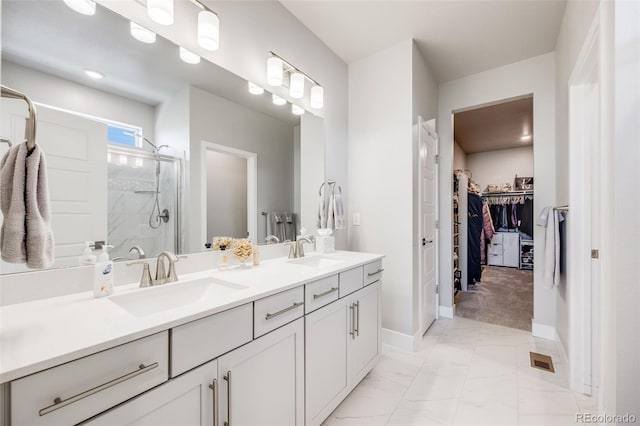 full bathroom with a sink, marble finish floor, a walk in closet, and a stall shower