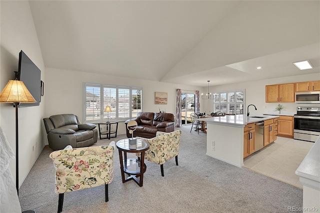 living area with a chandelier, a healthy amount of sunlight, light colored carpet, and high vaulted ceiling