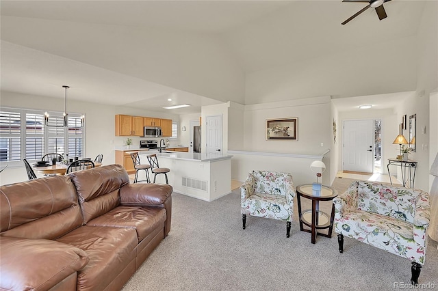 living room featuring a ceiling fan, visible vents, light colored carpet, and high vaulted ceiling