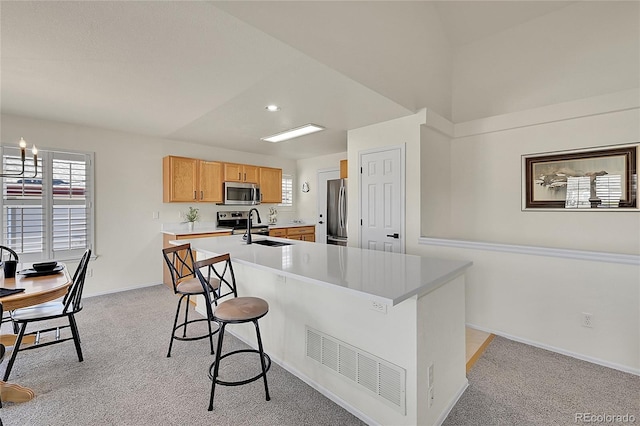 kitchen with light colored carpet, stainless steel appliances, a sink, visible vents, and a kitchen bar