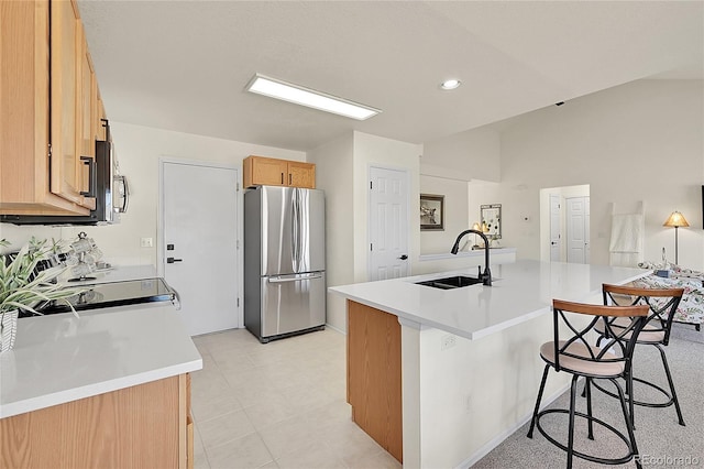 kitchen featuring light countertops, appliances with stainless steel finishes, a sink, and a kitchen breakfast bar