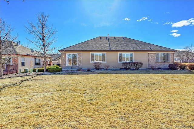 back of house featuring brick siding and a yard