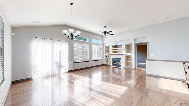 15926 Butterwort Cir, Parker, CO 80134 - unfurnished living room featuring built in features, hardwood / wood-style floors, a chandelier, a glass covered fireplace, and a ceiling fan