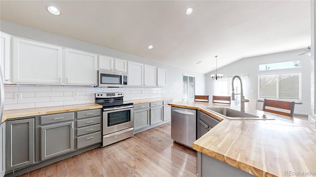 15926 Butterwort Cir, Parker, CO 80134 - kitchen with wood counters, stainless steel appliances, vaulted ceiling, gray cabinets, and light wood finished floors