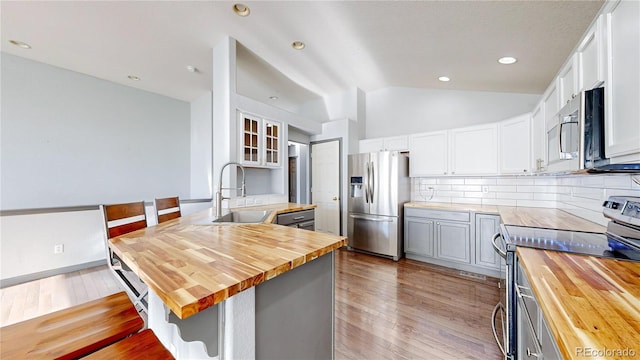 15926 Butterwort Cir, Parker, CO 80134 - kitchen with wood counters, appliances with stainless steel finishes, a peninsula, lofted ceiling, and a kitchen breakfast bar
