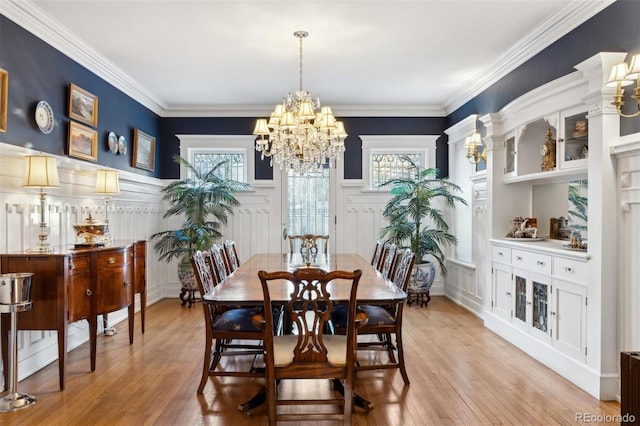 dining space featuring a healthy amount of sunlight, light hardwood / wood-style floors, ornamental molding, and a notable chandelier