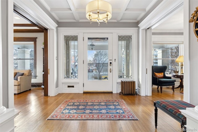 doorway to outside featuring beam ceiling, a notable chandelier, radiator, and coffered ceiling