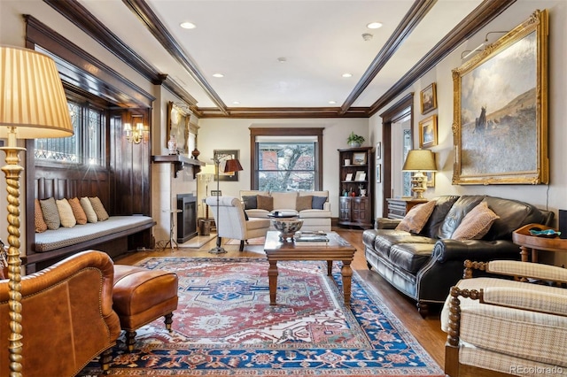 living area featuring a healthy amount of sunlight, hardwood / wood-style floors, and crown molding