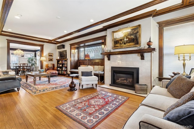 living room with a tile fireplace, light wood-type flooring, and crown molding