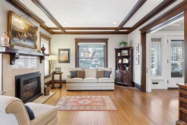 living room with a tiled fireplace, ornamental molding, hardwood / wood-style flooring, and beamed ceiling