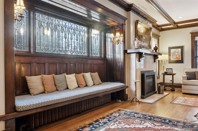 living area featuring a tiled fireplace, crown molding, and light hardwood / wood-style flooring