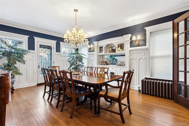 dining space with ornamental molding, an inviting chandelier, hardwood / wood-style flooring, and radiator