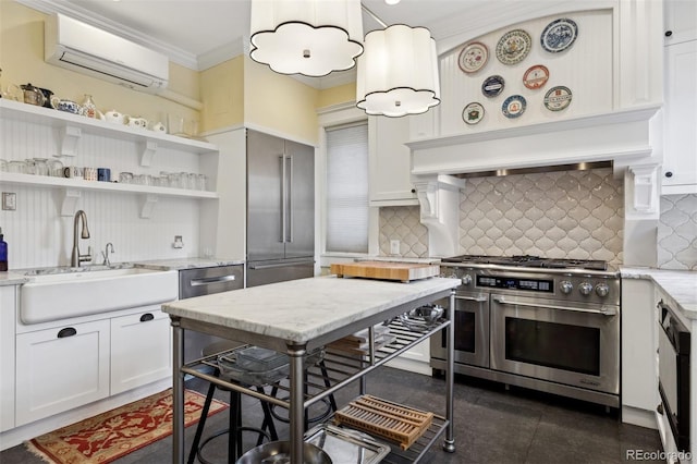 kitchen with light stone countertops, a wall mounted air conditioner, sink, white cabinetry, and premium appliances