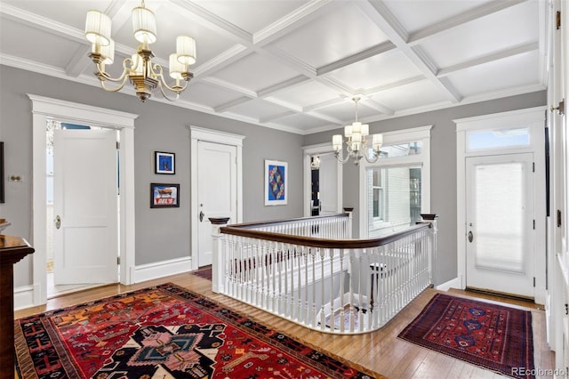 entryway with a chandelier, hardwood / wood-style floors, beam ceiling, ornamental molding, and coffered ceiling