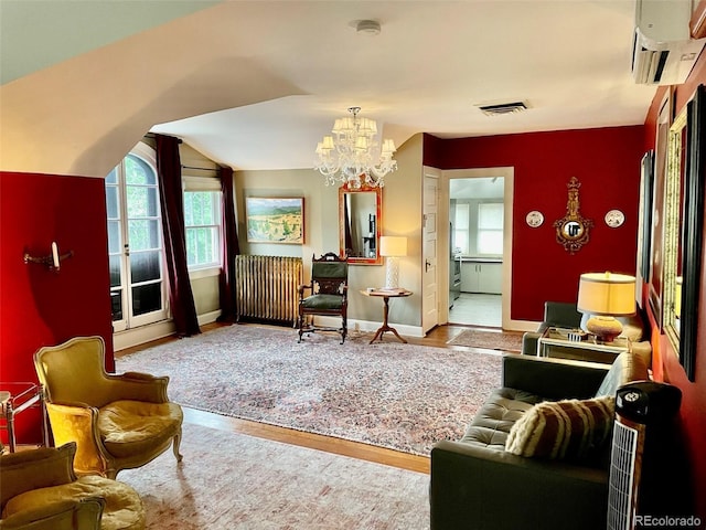 sitting room featuring hardwood / wood-style flooring, a chandelier, a wealth of natural light, and a wall mounted air conditioner