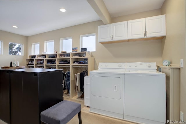 washroom with cabinet space, a healthy amount of sunlight, washer and clothes dryer, and light carpet