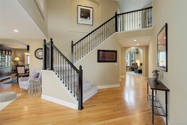 staircase with arched walkways, wood finished floors, and a wealth of natural light