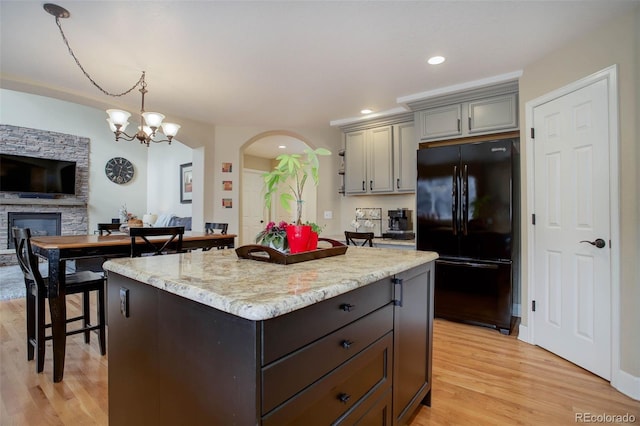 kitchen featuring arched walkways, gray cabinets, freestanding refrigerator, and light wood-type flooring