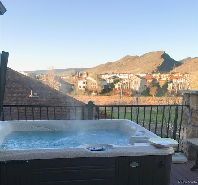 deck with a hot tub, a mountain view, and a residential view