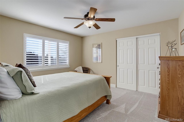 bedroom with ceiling fan, light colored carpet, baseboards, and a closet