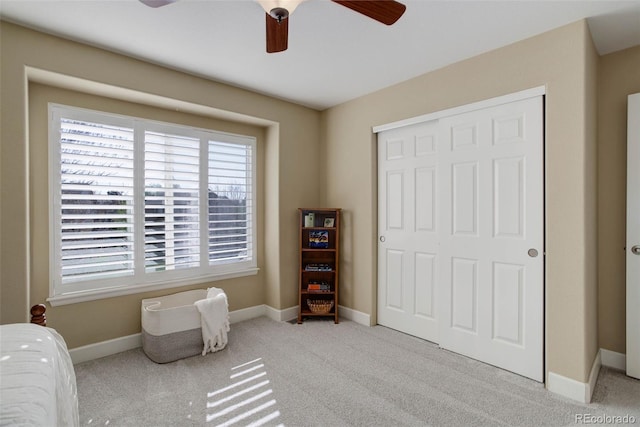 bedroom with carpet floors, a ceiling fan, baseboards, and a closet
