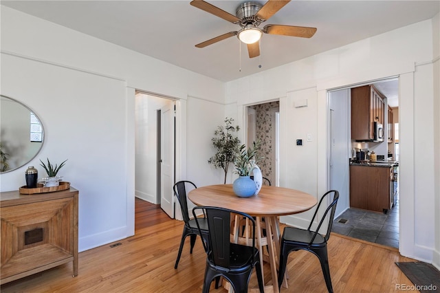 dining space featuring light wood-type flooring, a ceiling fan, and baseboards