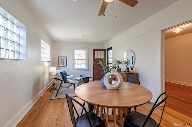 dining space featuring light wood-style flooring, baseboards, and a ceiling fan