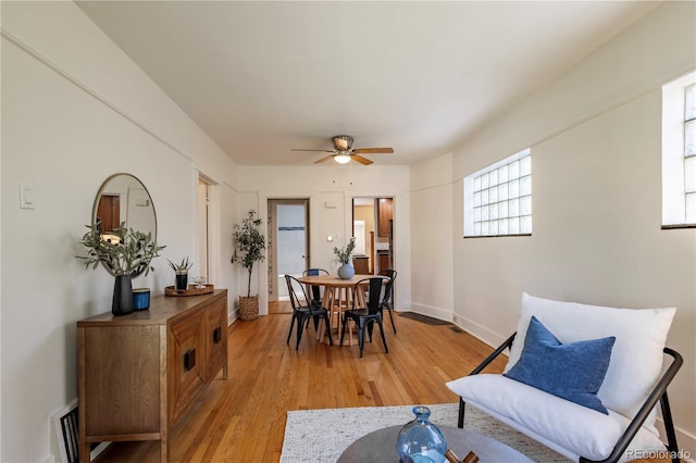 dining room with a ceiling fan, light wood finished floors, and baseboards