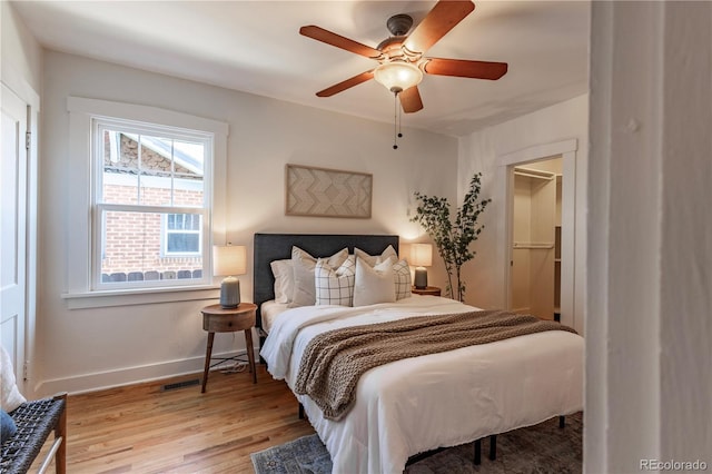 bedroom with baseboards, light wood finished floors, and ceiling fan