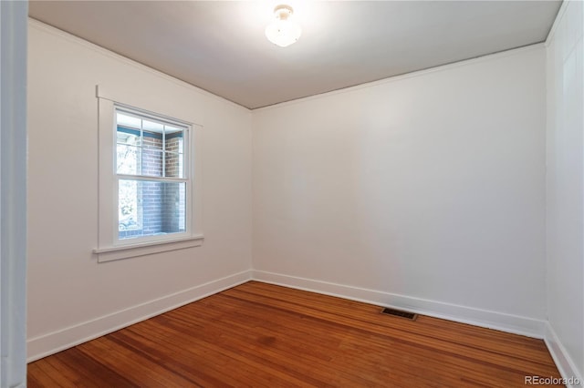 unfurnished room featuring wood finished floors, baseboards, and crown molding