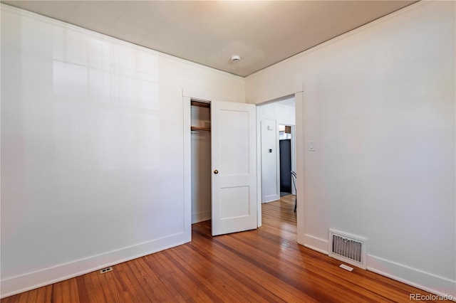 unfurnished bedroom with baseboards, hardwood / wood-style flooring, and a closet
