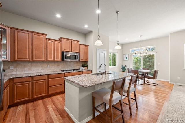 15414 Xenia Ct, Thornton, CO 80602 - kitchen with appliances with stainless steel finishes, light wood finished floors, brown cabinetry, tasteful backsplash, and recessed lighting