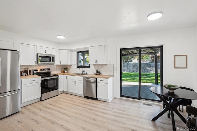 kitchen featuring stainless steel appliances, a sink, healthy amount of natural light, and wooden counters