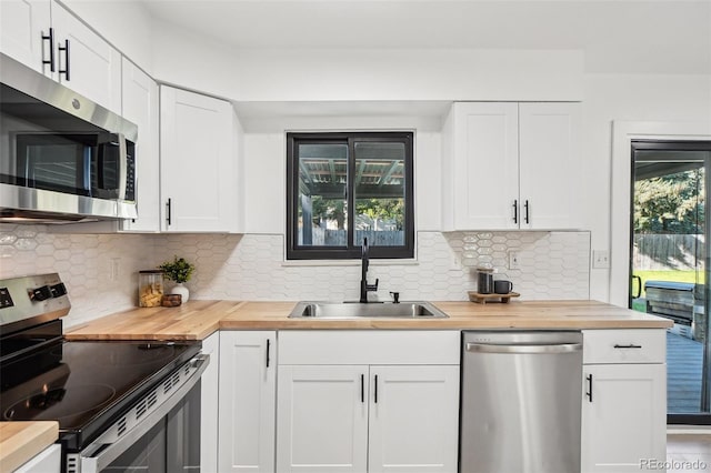 kitchen featuring appliances with stainless steel finishes, a sink, wooden counters, and white cabinetry
